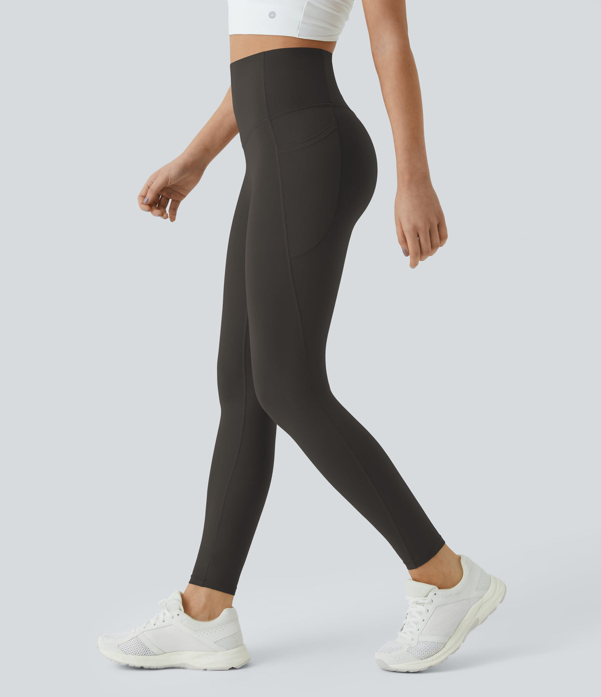 Side view of a model walking in Celeste L'Amour Hazelnut Black high-waisted 7/8 leggings with side pockets